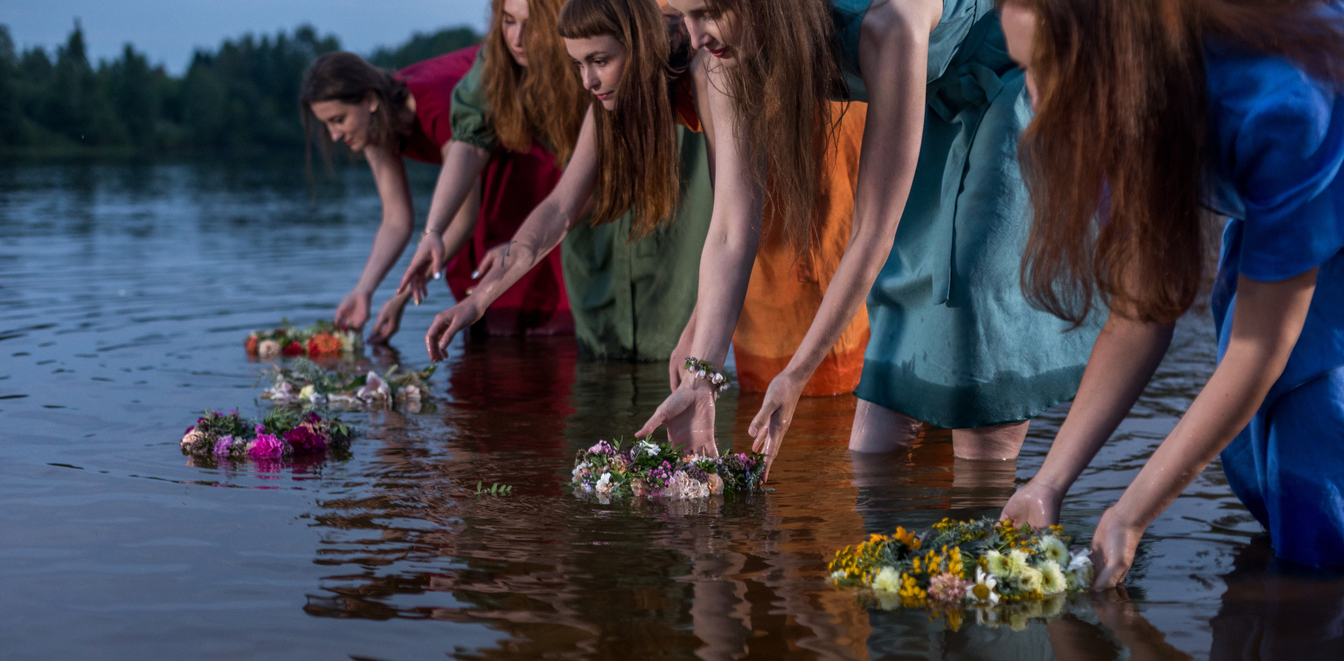 Lovely girls in flower wreaths in nature. Ancient pagan origin celebration concept. Summer solstice day. Mid summer. Ancient rituals.